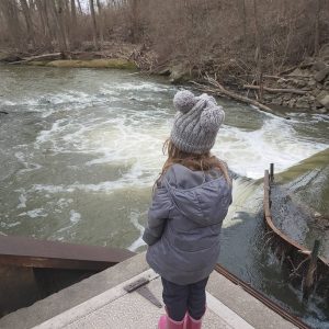 child watching a rushing creek